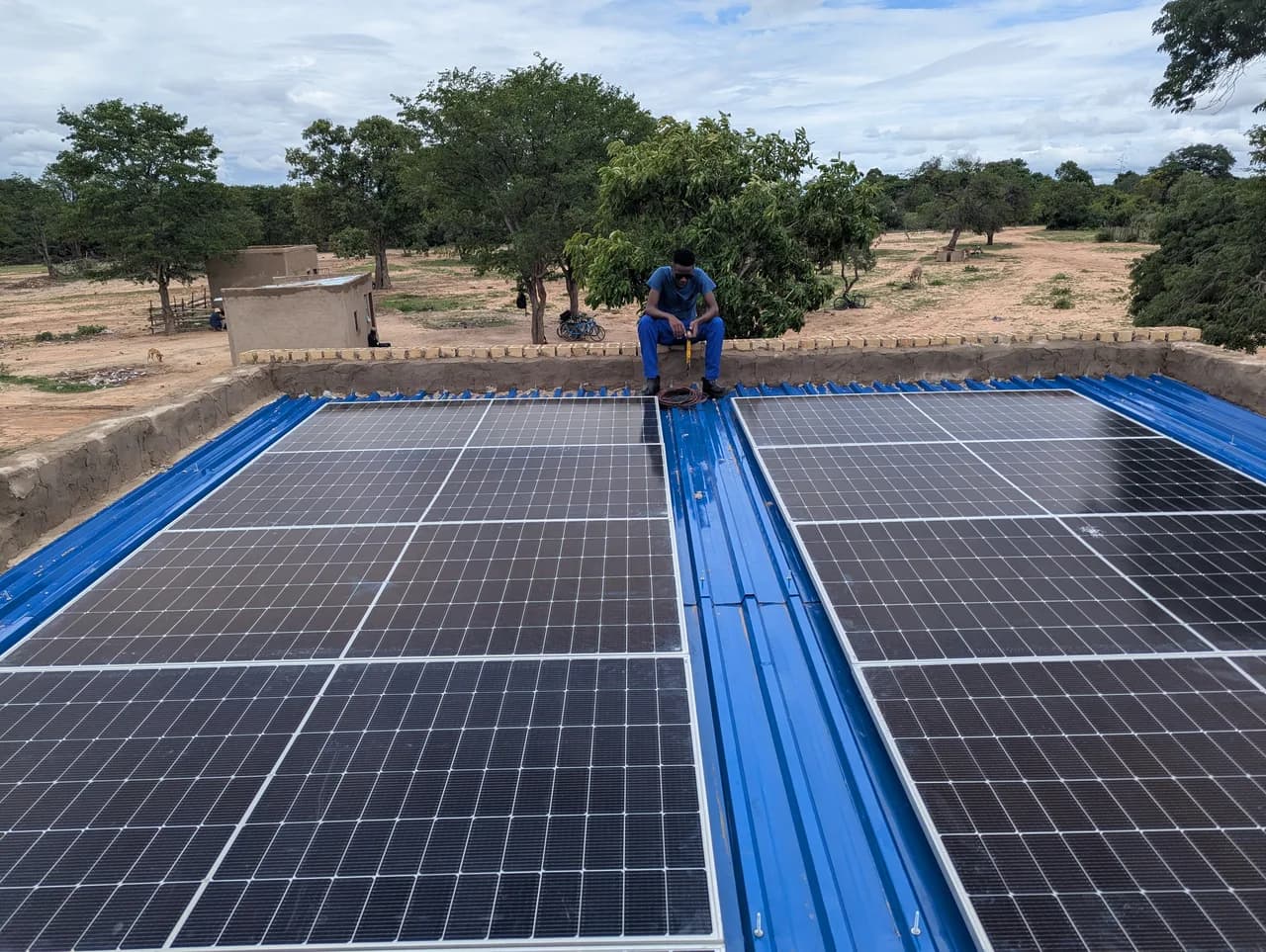 Finished rooftop solar array on a metal roof, with a technician at the ridge